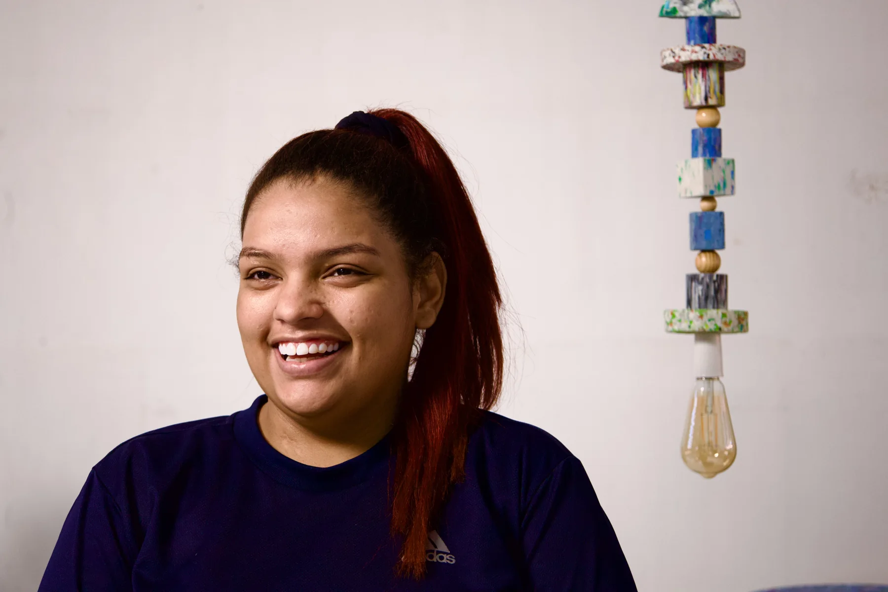 Retrato de uma artesã junto a uma luminária de plástico reciclado