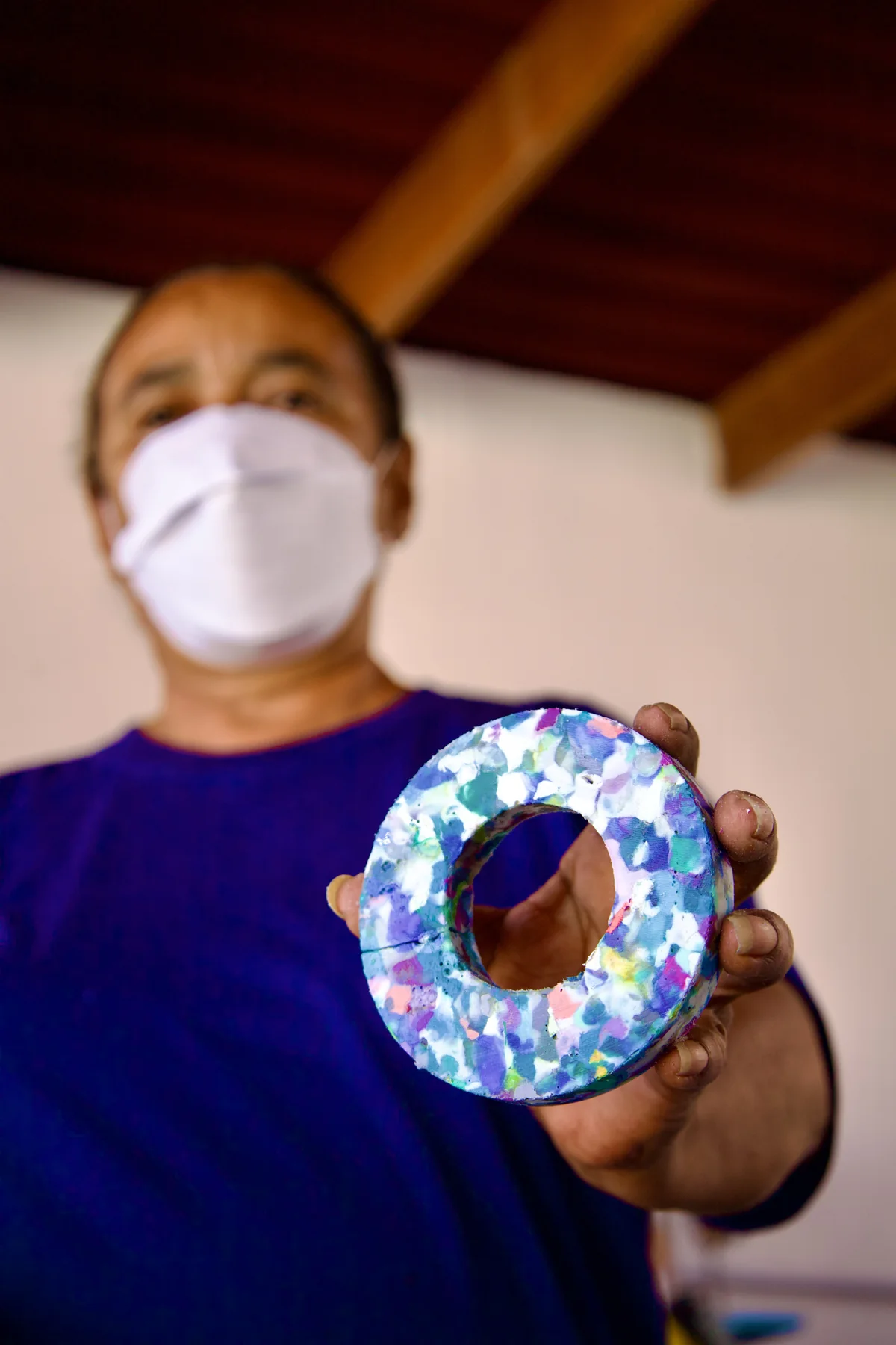 Artesã apresentando uma peça circular de plástico reciclado