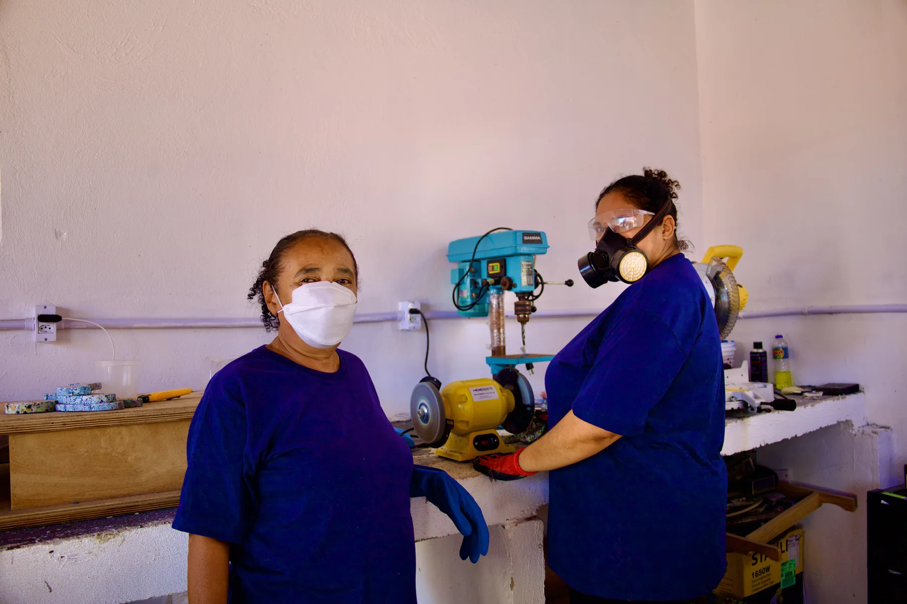 Duas artesãs trabalhando na oficina com equipamentos de proteção