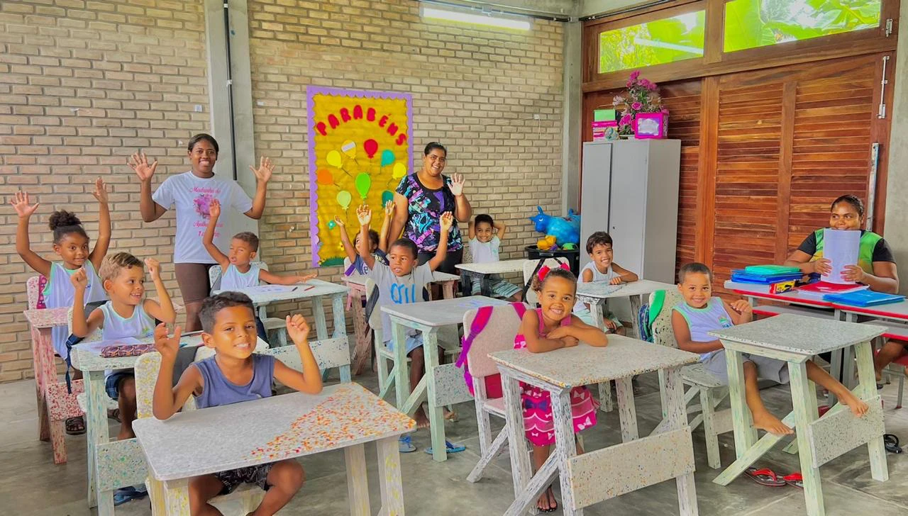 Crianças sentadas em cadeiras e mesas em uma sala de aula, em registro da apresentação institucional da ZR0